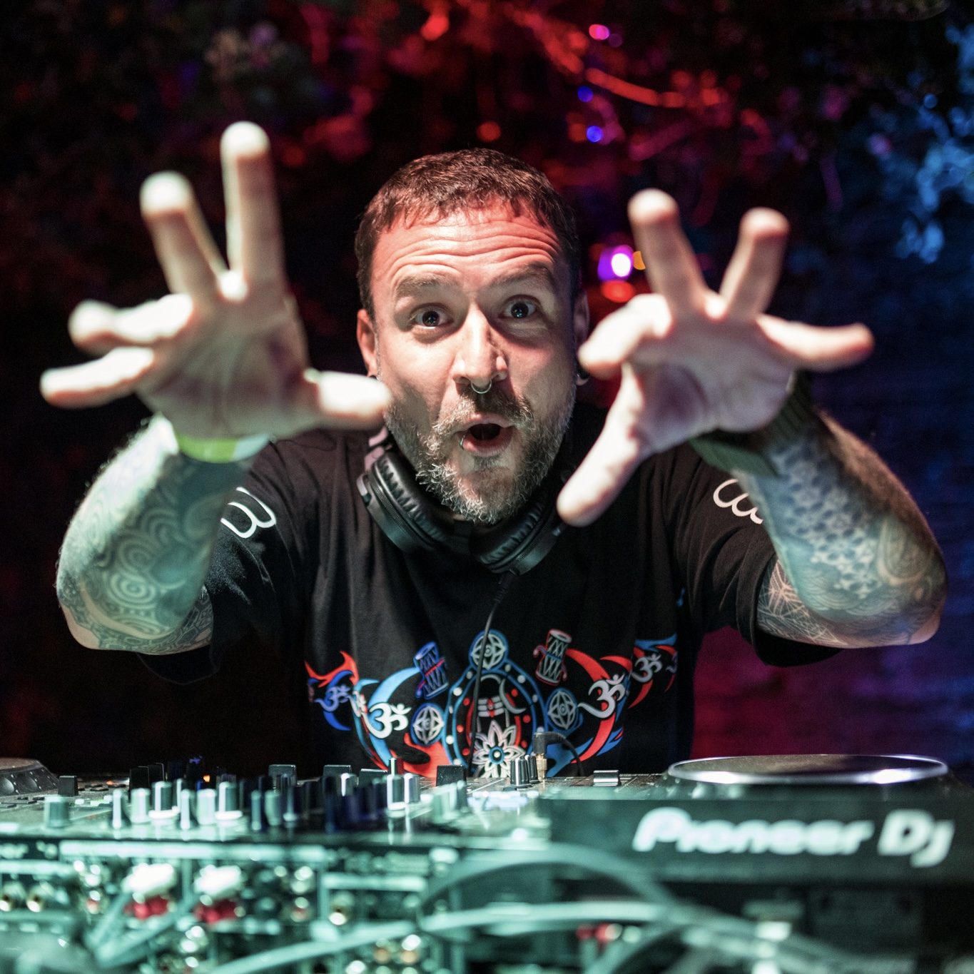 Amplify reaching toward the camera behind Pioneer decks