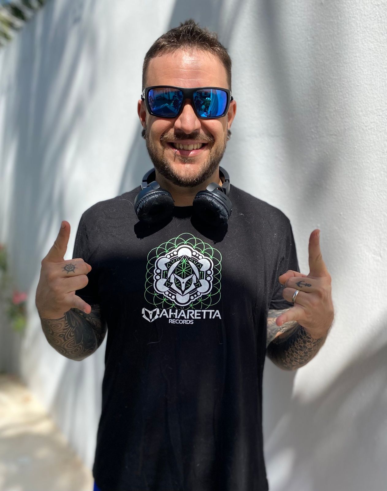Andrew Olavarrieta, Amplify, smiling in a Maharetta Records t-shirt against a white wall